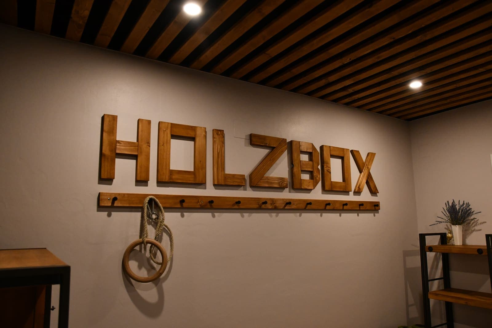 HOLZBOX-Schriftzug aus Holzbalken über der Garderobenleiste