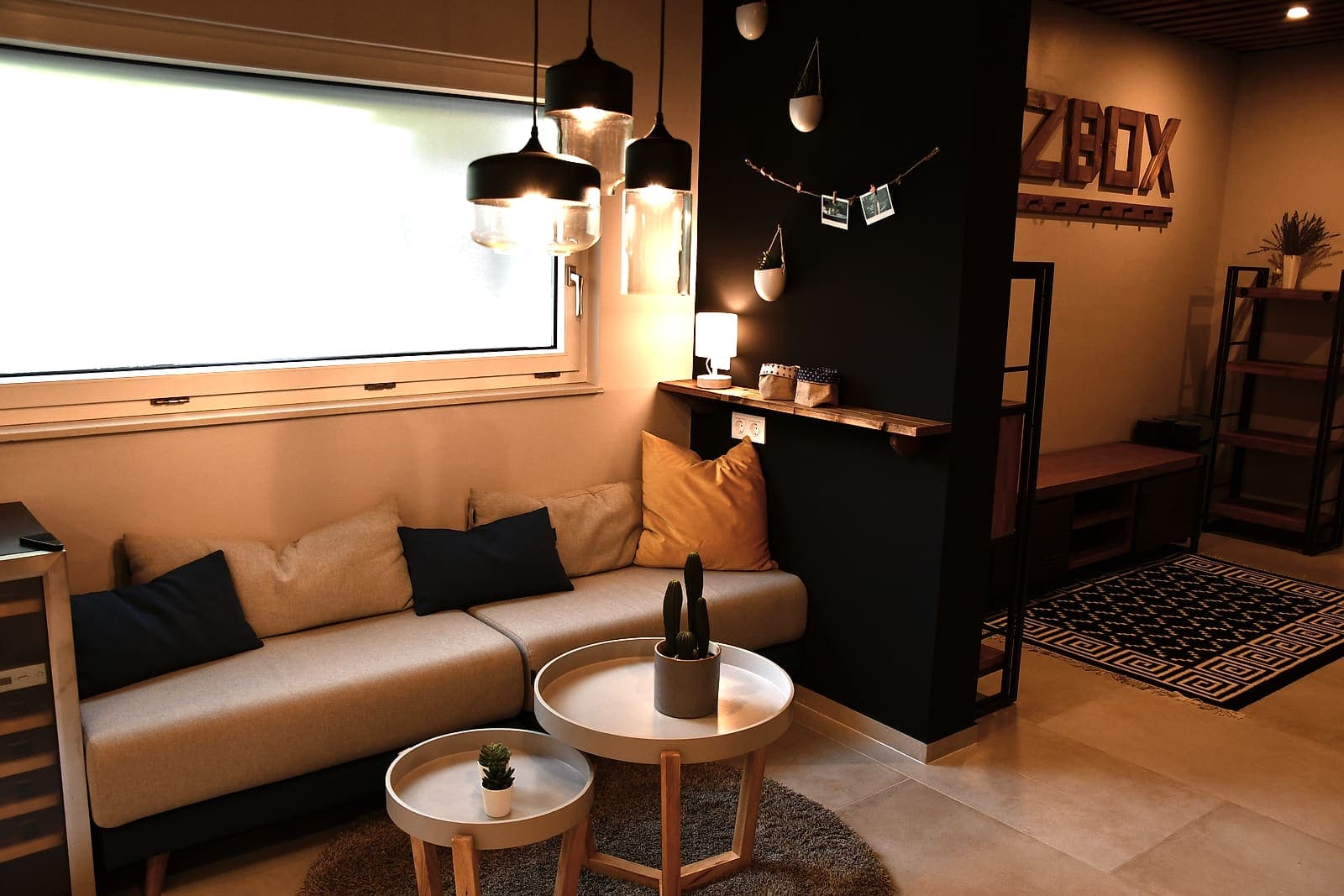 Lounge-Ecke mit Sofa, Beistelltischen und HOLZBOX-Wortmarke aus Holz